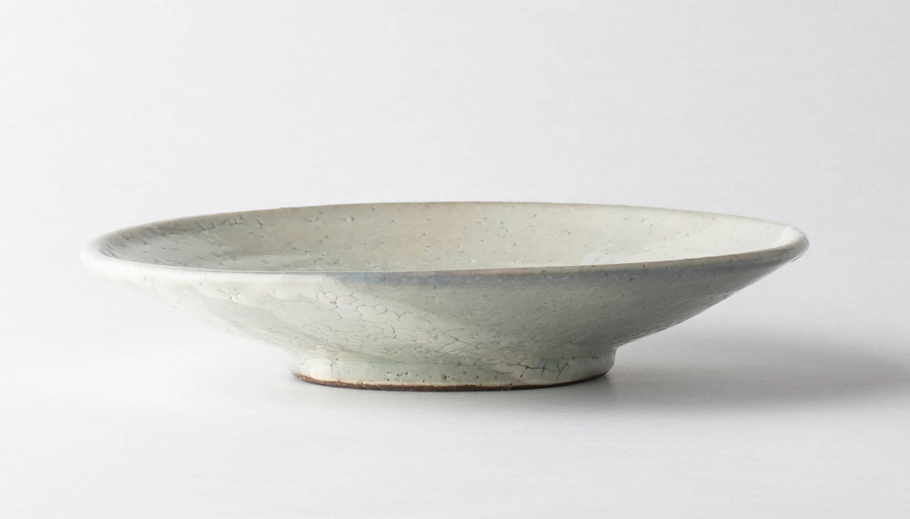 Handmade ceramic bowl, pale gray with speckled crackle glaze and low, wide shape.