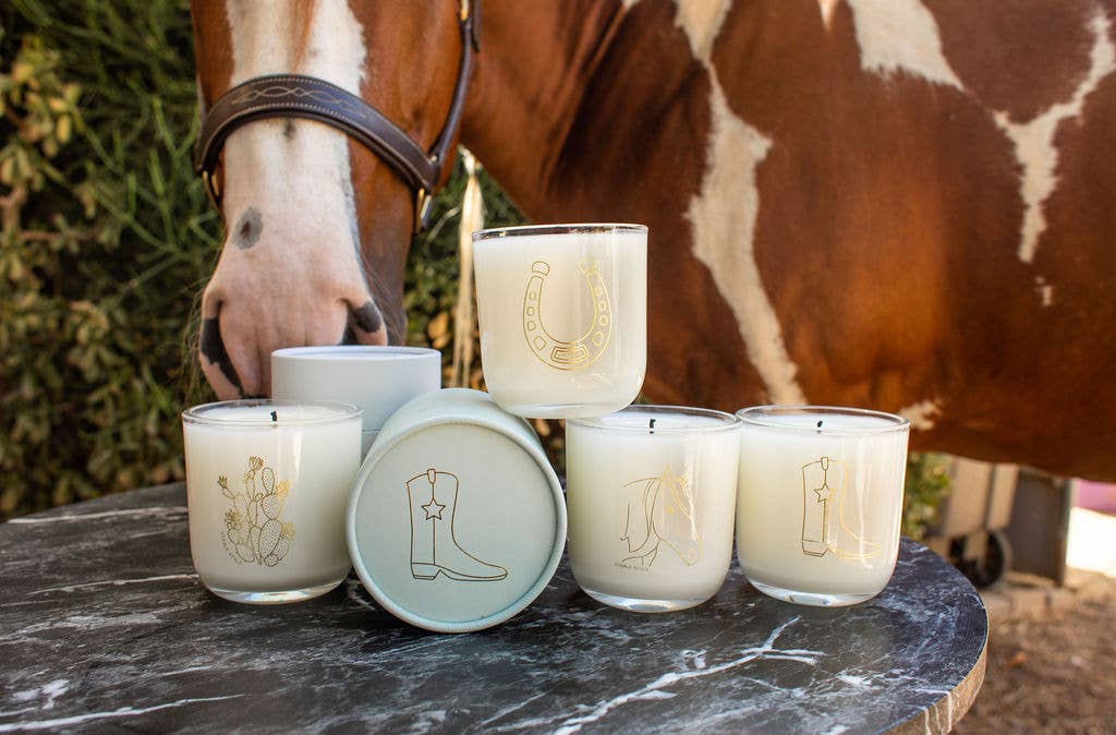 Horseshoe soy wax candle among glass candles with gold western-themed designs