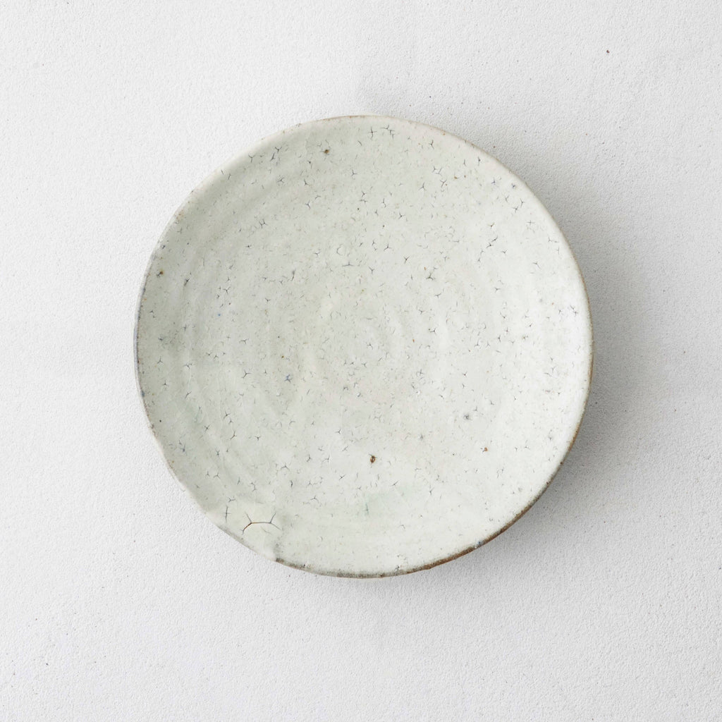 Round ceramic side plate, speckled off-white glaze with small pitted marks