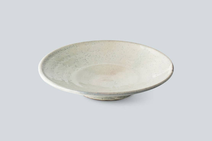 Handmade ceramic bowl in pale gray with speckled crackle glaze and wide rim.