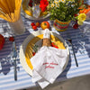 White napkin with red embroidered Italian saying, draped through a woven napkin ring