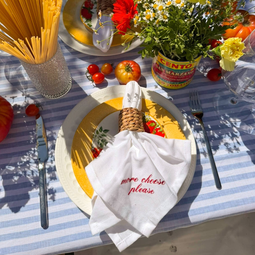 White napkin with red embroidered Italian saying, draped through a woven napkin ring