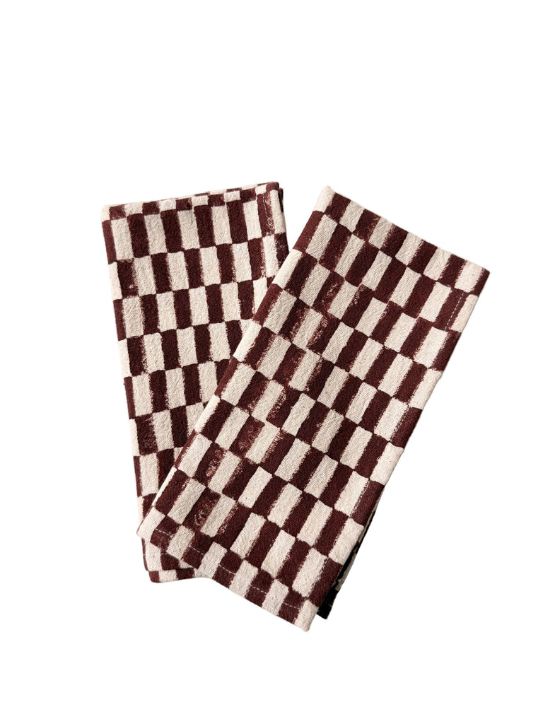 Set of 2 checkered napkins, brown and white, folded and slightly overlapping