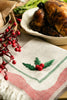Cream tea towel with holly berry embroidery and green/red striped edge with fringe