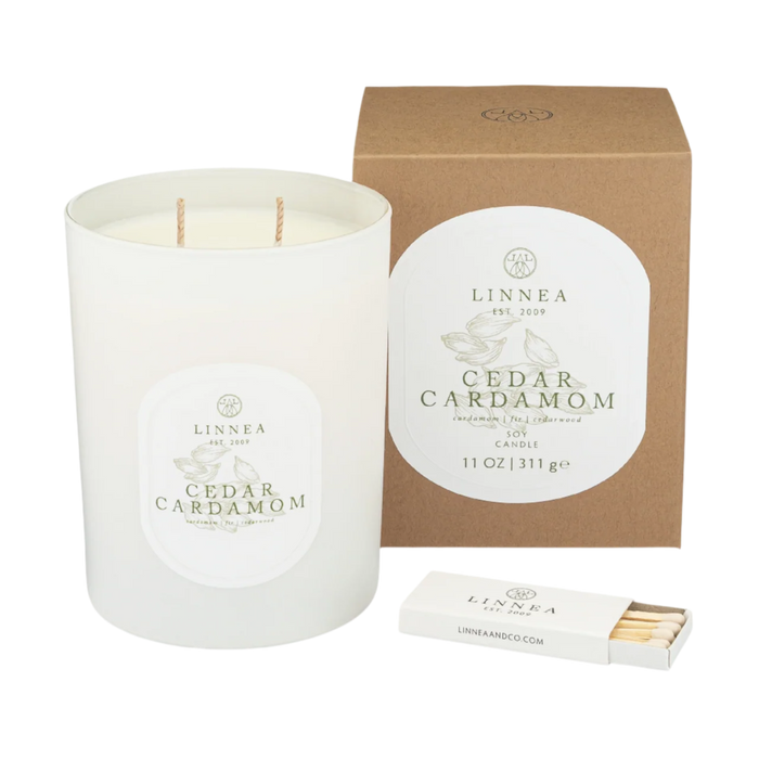 White glass jar candle with two wicks; Cedar Cardamom scent label on jar