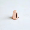 Copper-tone candle sharpener, metal cone with dark interior.