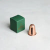 Copper-tone candle sharpener beside green product box.