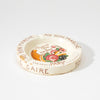Round cream ceramic ashtray with colorful fruit print and French text around rim