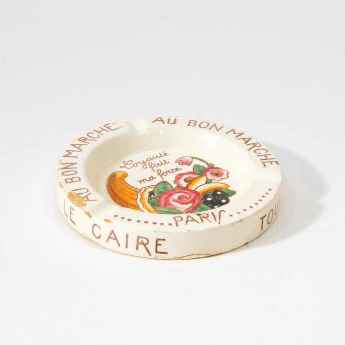 Round cream ceramic ashtray with colorful fruit print and French text around rim