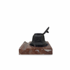 An antique-style inkwell with a dark metal body and an open lid, mounted on a rectangular reddish-brown marble base, shown against a plain white background.