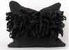 A black dreadlocks pillow made of natural wool, with a textured and voluminous appearance.
