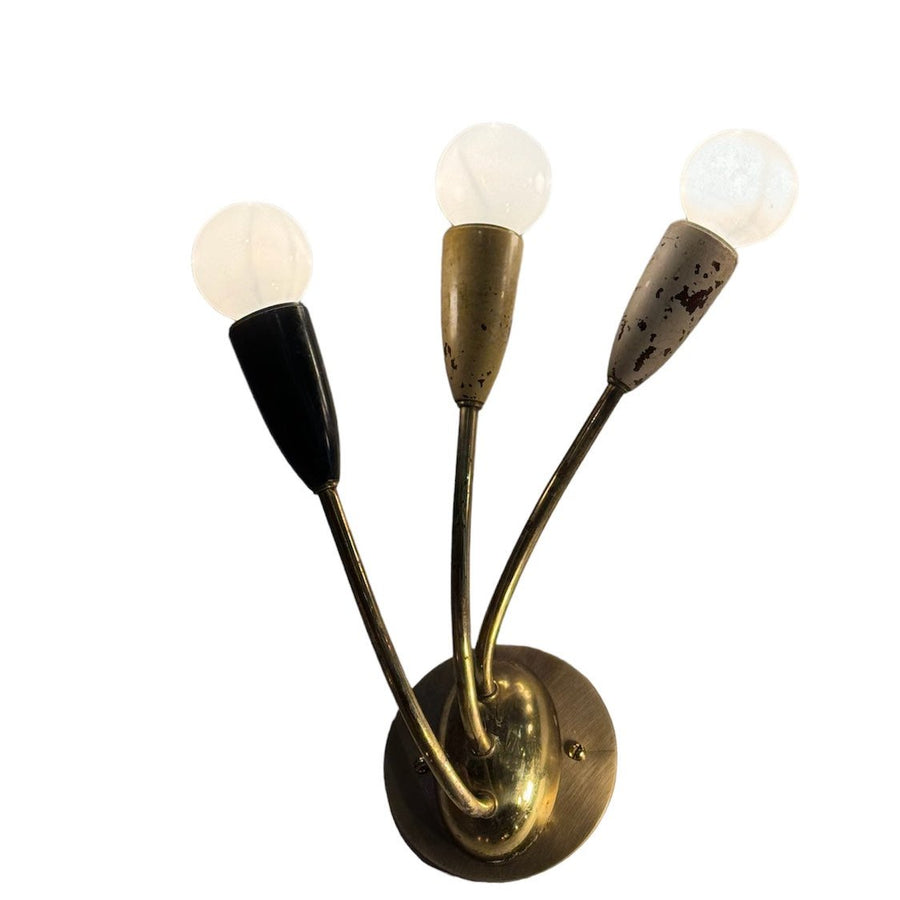 Antique wall sconce with round brass backplate and three curved arms with frosted glass shades