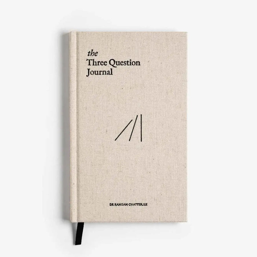 Linen-textured journal cover with “The Three Question Journal” title and black ribbon bookmark