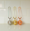 Set of three stainless steel tea strainers with mesh balls in silver, gold, and rose gold