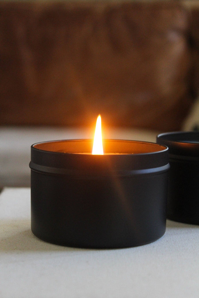 Close-up of a black candle tin with a lit wick