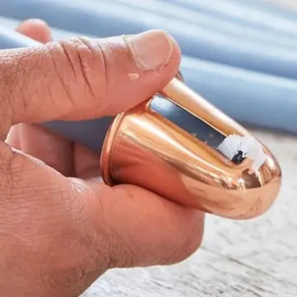 Hand using copper-tone candle sharpener to sharpen candle end.