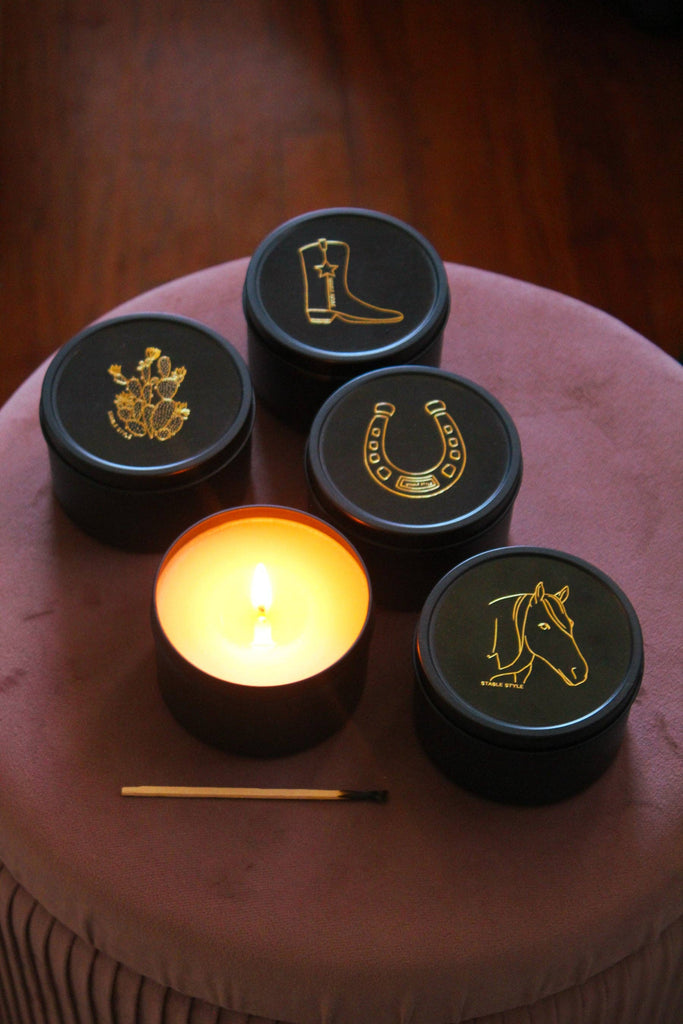 Cowboy boot candle tin among other illustrated tins, with one candle lit