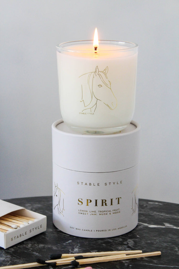 Horse soy wax candle in glass with a lit wick, shown atop its Spirit product box.