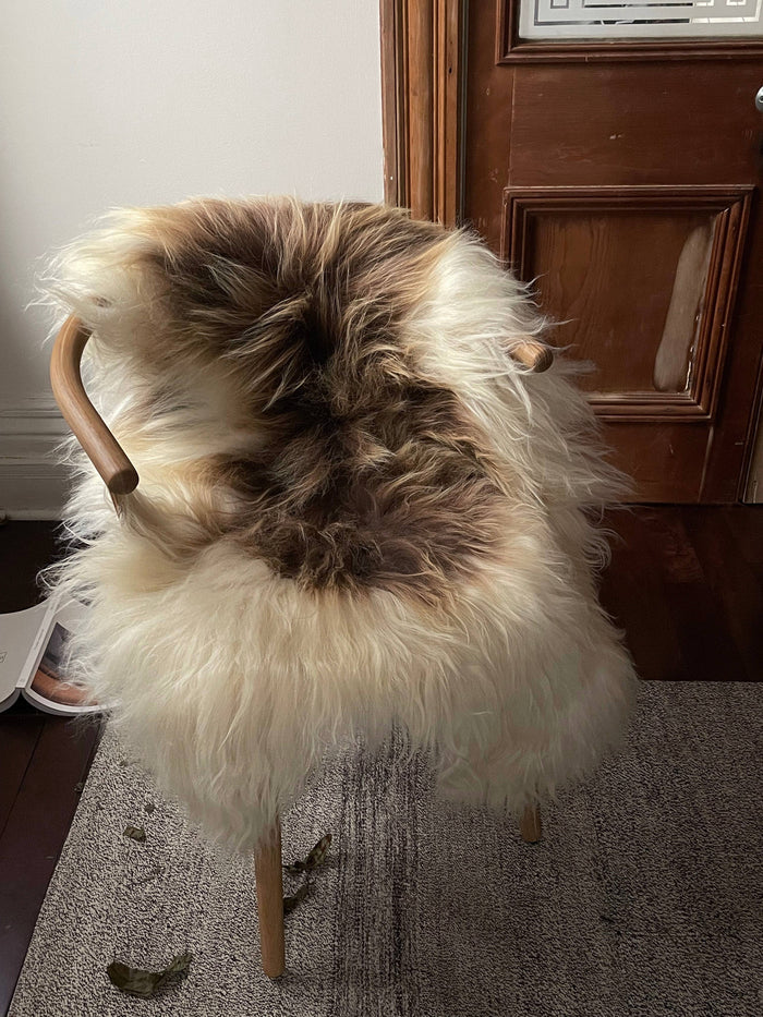 Spotted sheepskin throw rug with cream, brown, and dark taupe hide pattern