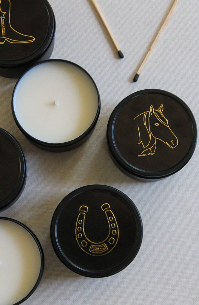 Black candle tins with white wax and lids featuring horse and horseshoe designs