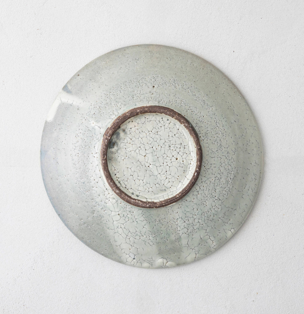 Top view of handmade ceramic bowl with pale gray crackle glaze and brown rim ring.