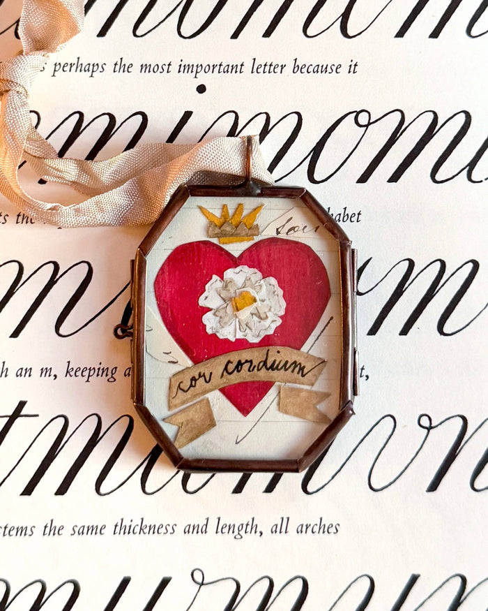 Handmade heart-shaped ornament with red center and white flower inside round frame