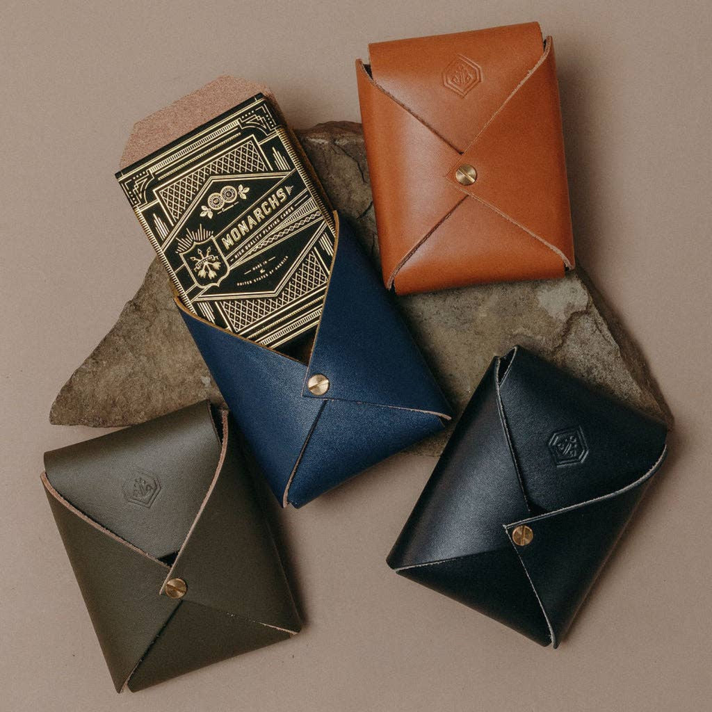 Leather playing card cases set in tan, blue, and dark tones with brass snaps