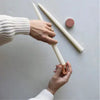 Copper-tone candle sharpener tapering white taper candles with hands.