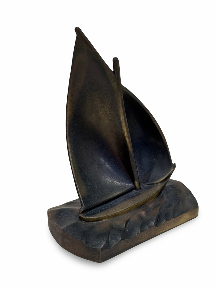Bronze sailboat sculpture on a white background