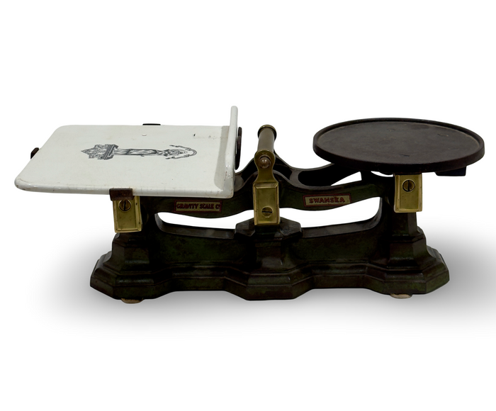 Antique cast iron scale with brass frame, round dial, and white weighing platform