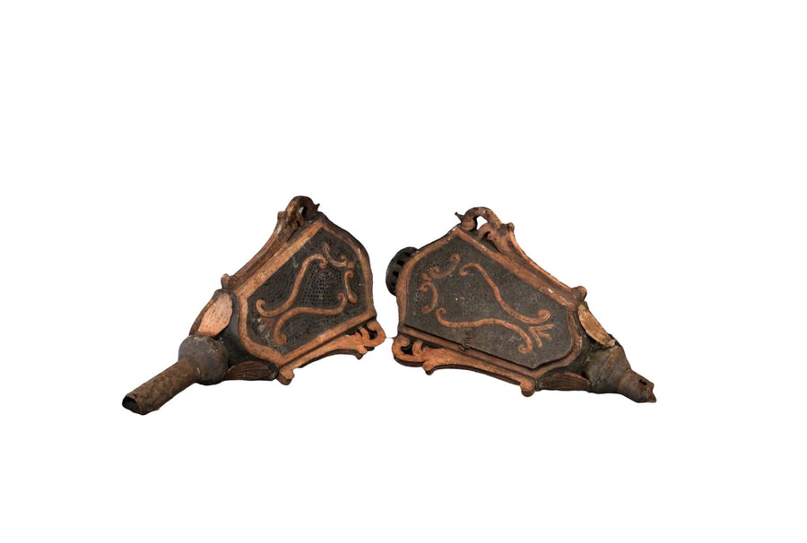 Antique wall sconces, ornate dark brown panels with curved metal arms